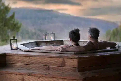 Man and woman enjoying a candlelit hot tub while looking at the view