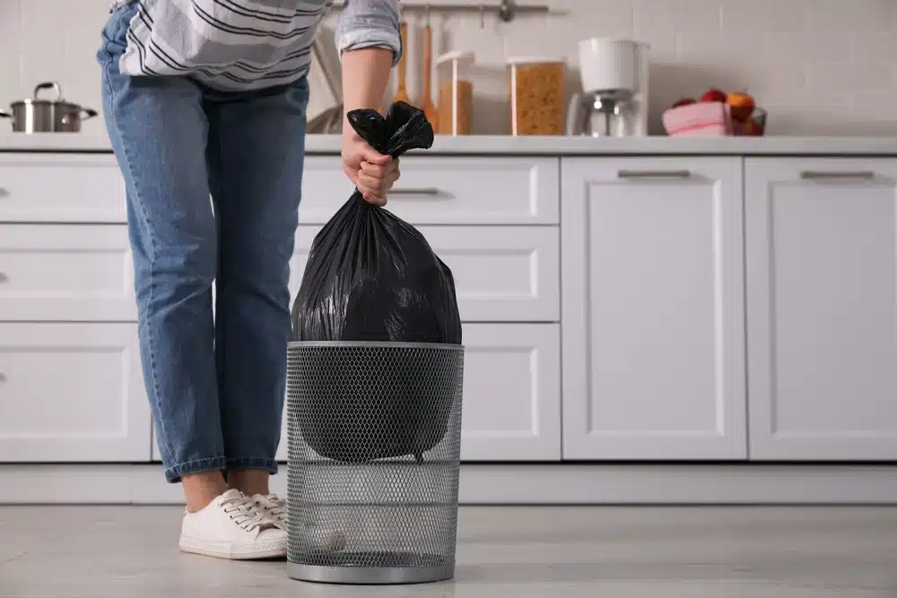 person taking out kitchen trash bag