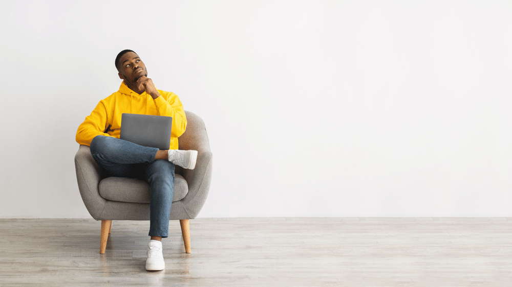 man pondering with laptop on lap