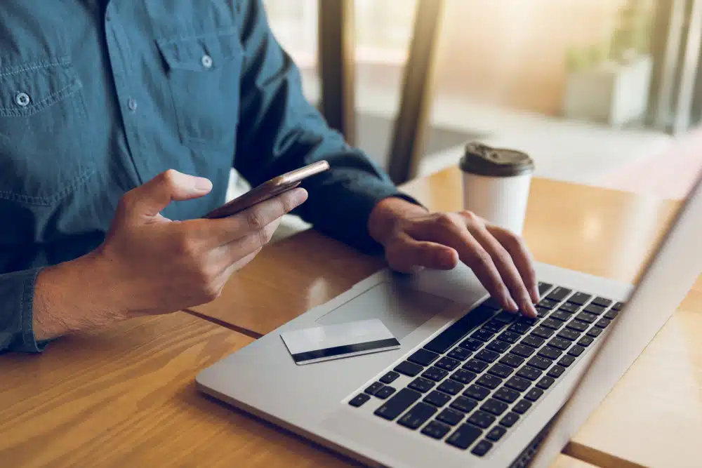 man on laptop and phone with credit card on table