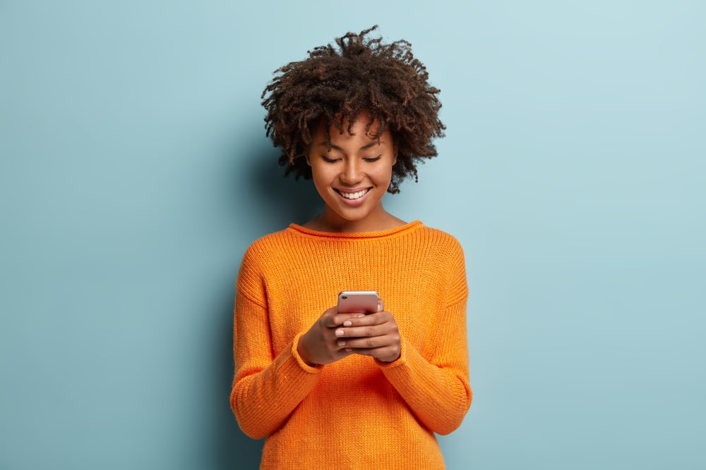 woman in orange sweater on phone