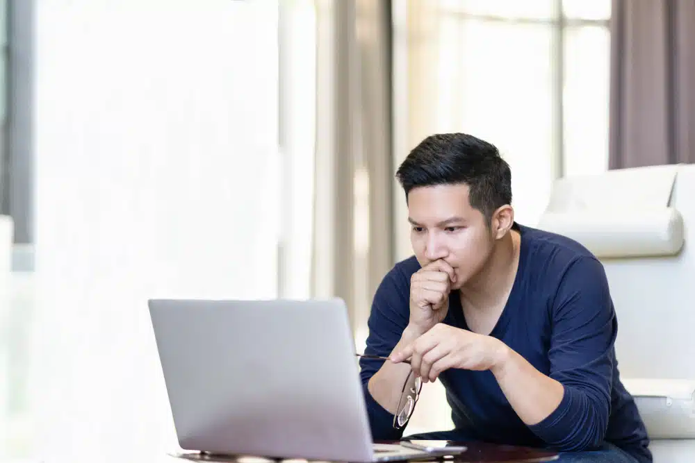 man on laptop holding glasses