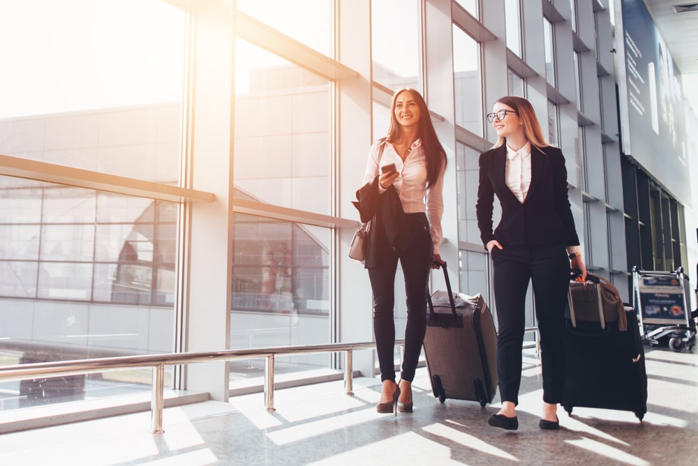 Two businesswomen walking with luggage at an airport