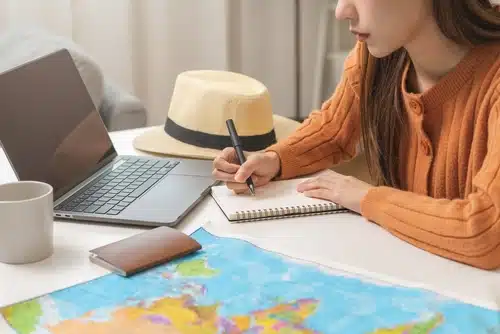 woman notetaking with map and computer