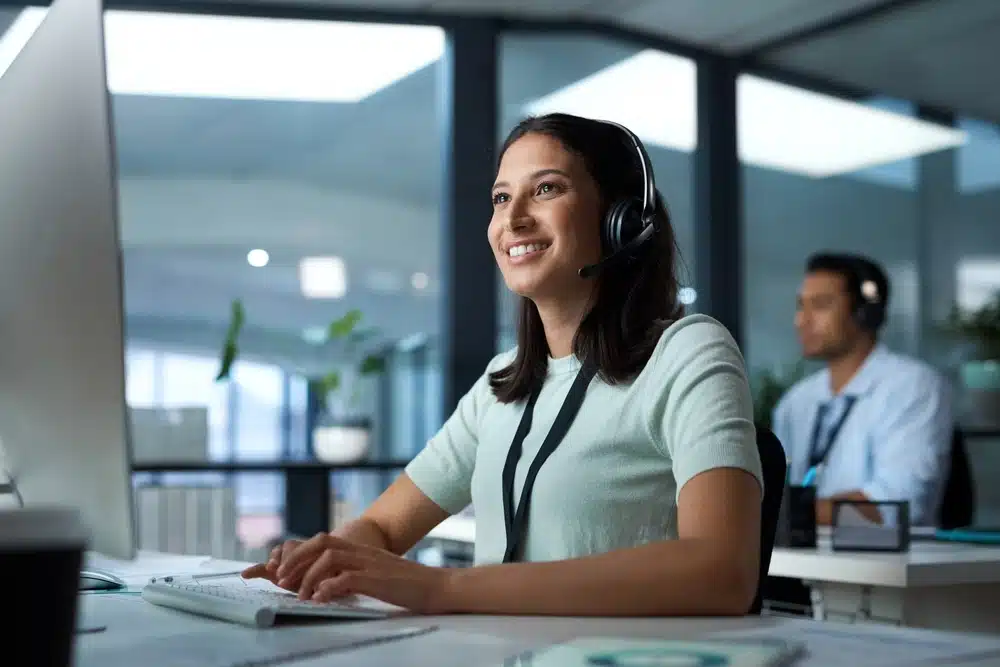 Customer Service Representative: A smiling woman with a headset working at a desk in an office.